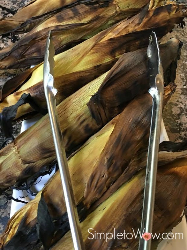 corn in husk on grill with tongs